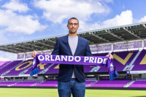 Image of Seb Hines holding an Orlando Pride scarf.