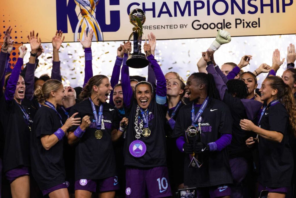 Image of the Orlando Pride raising the NWSL Championship trophy, illustrating the success the team achieved in 2024.