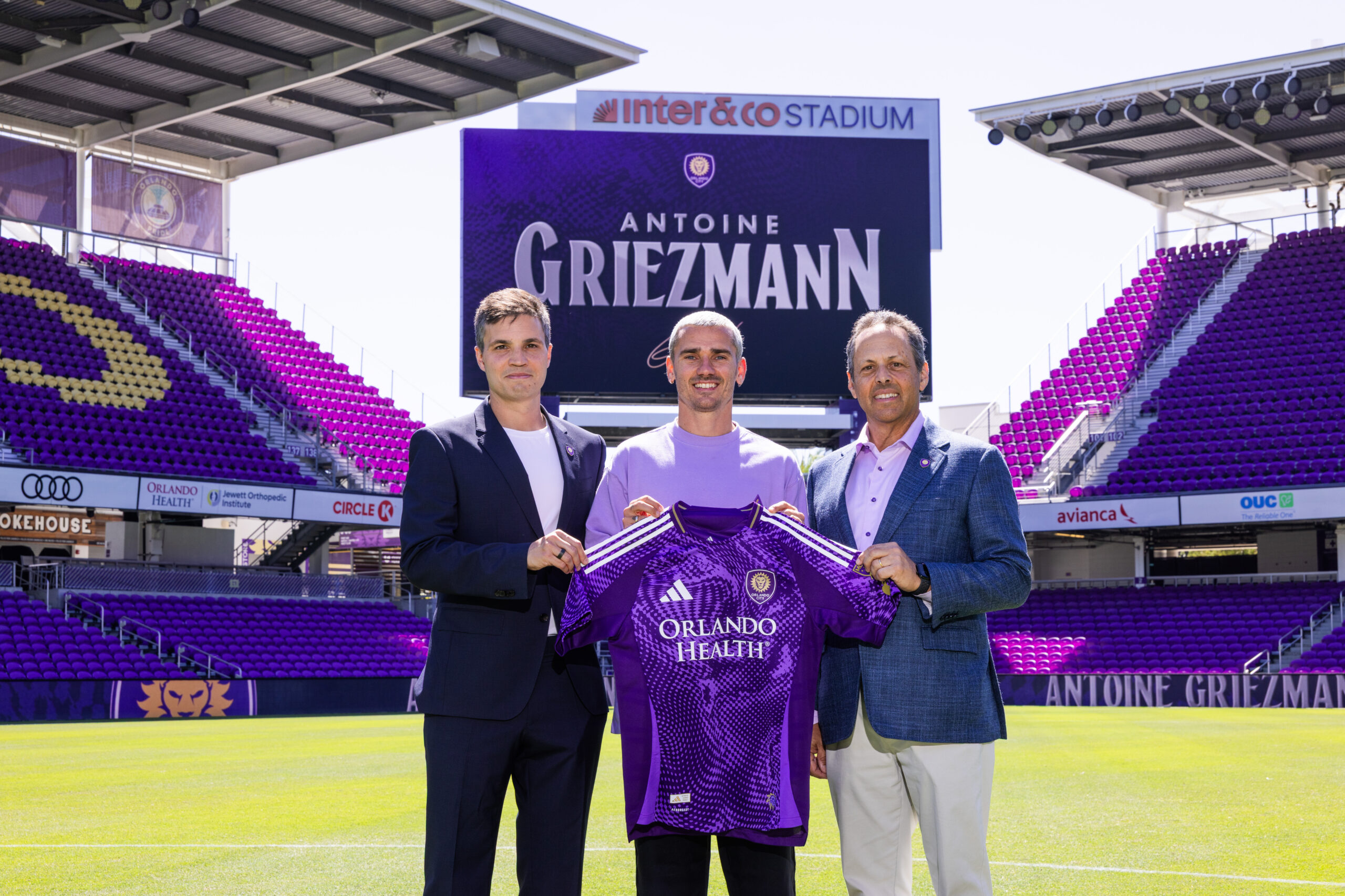 Image of Antoine Griezmann posing with his Orlando City kit alongside Ricardo Moreira and Mark Wilf.
