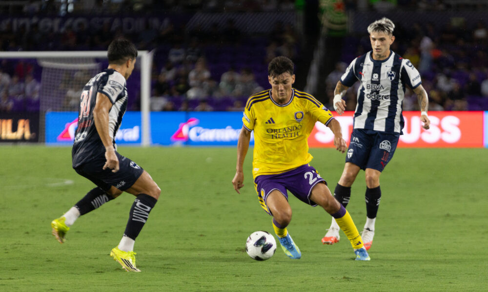 Image of Justin Ellis dribbling the ball between two Monterrey defenders.