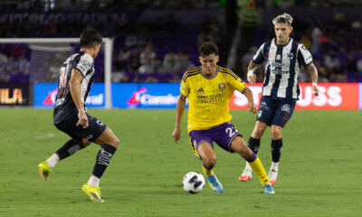 Image of Justin Ellis dribbling the ball between two Monterrey defenders.