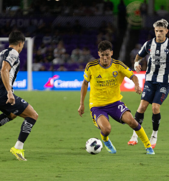 Image of Justin Ellis dribbling the ball between two Monterrey defenders.