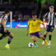 Image of Justin Ellis dribbling the ball between two Monterrey defenders.